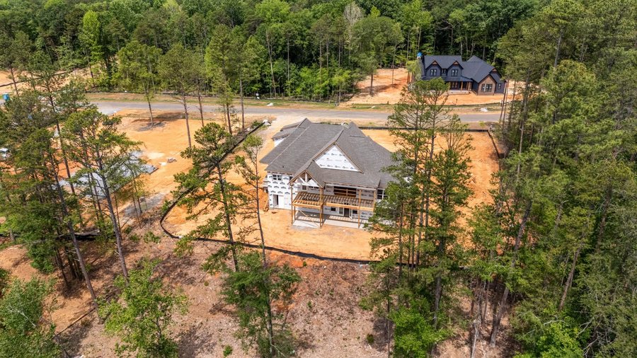 Aerial view of Southern Pine Lake with a home under frame, a completed home beyond, and cleared homesites along the road.