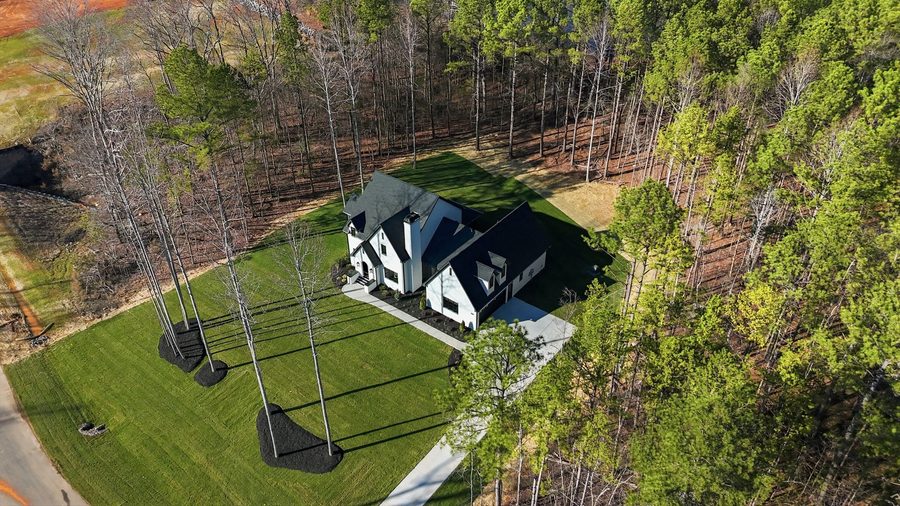 February 2026 aerial of a completed Harding custom home at Southern Pine Lake, set on a cleared acre plus homesite ringed by pine and hardwood.