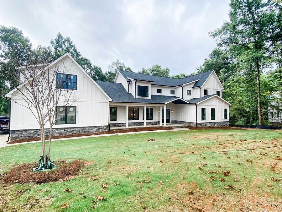 White board and batten custom home with a stone foundation and a deep covered porch.