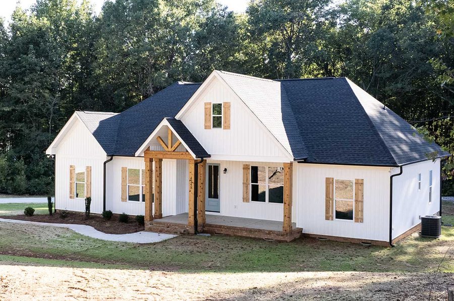 White custom home with cedar porch posts, cedar shutters, and a timber gable bracket.