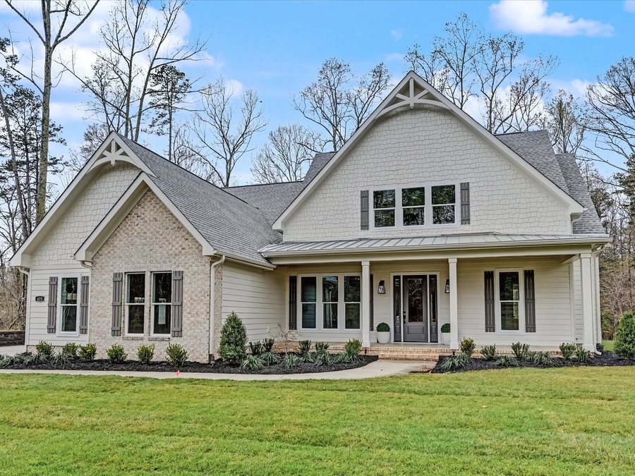 Cream brick and shingle custom home with a full width front porch and standing seam porch roof.