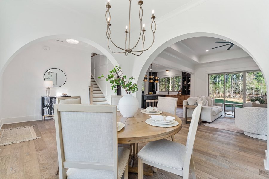 Dining and living space seen through paired arched openings, with sliding glass to the rear lawn.
