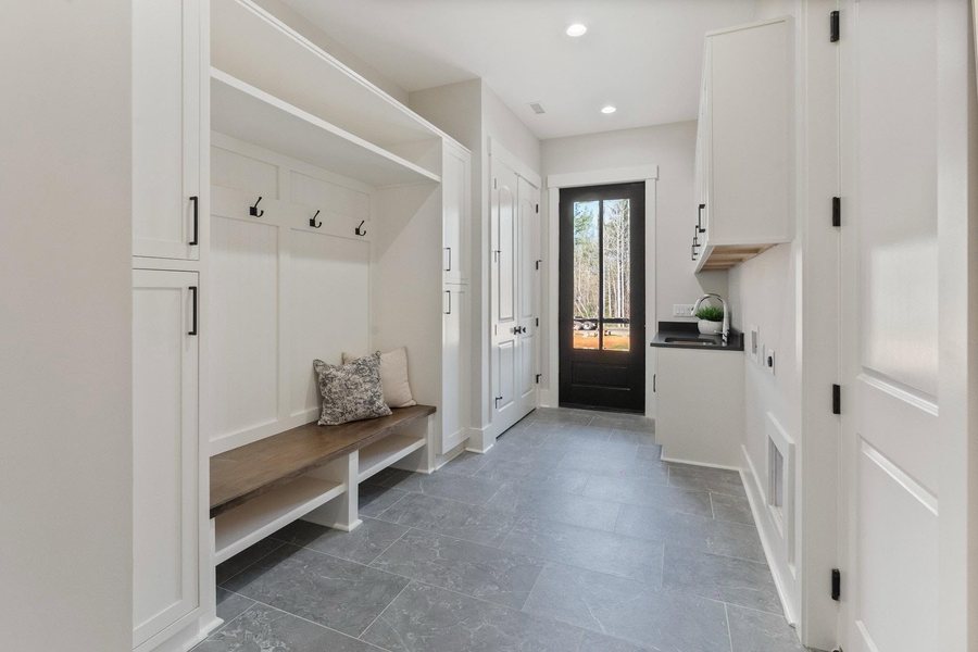 Drop zone with a built in bench, hooks, tall storage, and a laundry run to the rear door.